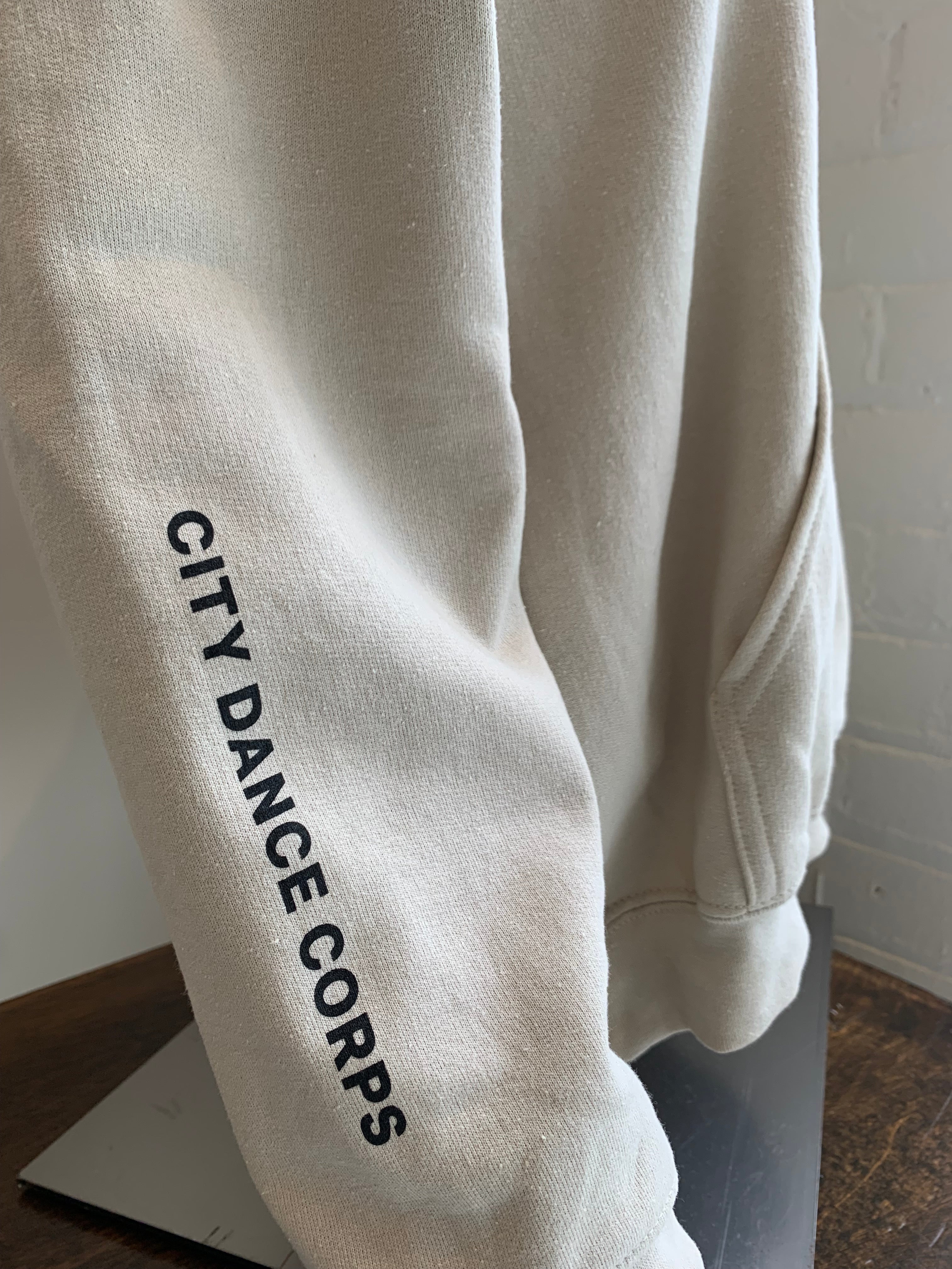 Beige hoody for dancers for warm up and cool down. Dance More Live More logo.